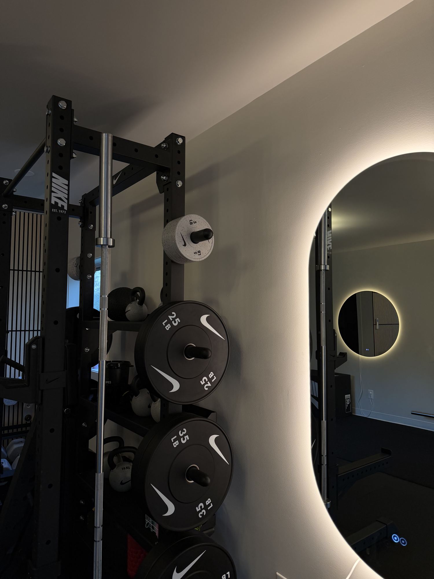 The backlit oval mirror beside the rack at Evolve